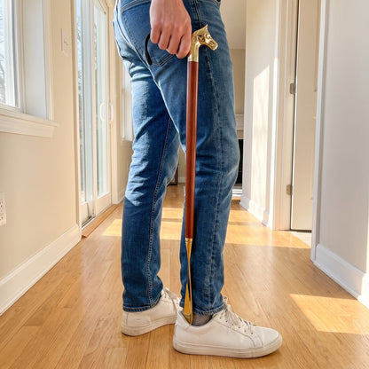 Putting on a sneaker standing up with the long horse-head shoe horn
