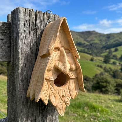 Wood spirit birdhouse hanging on an old fence post on Banks Peninsula