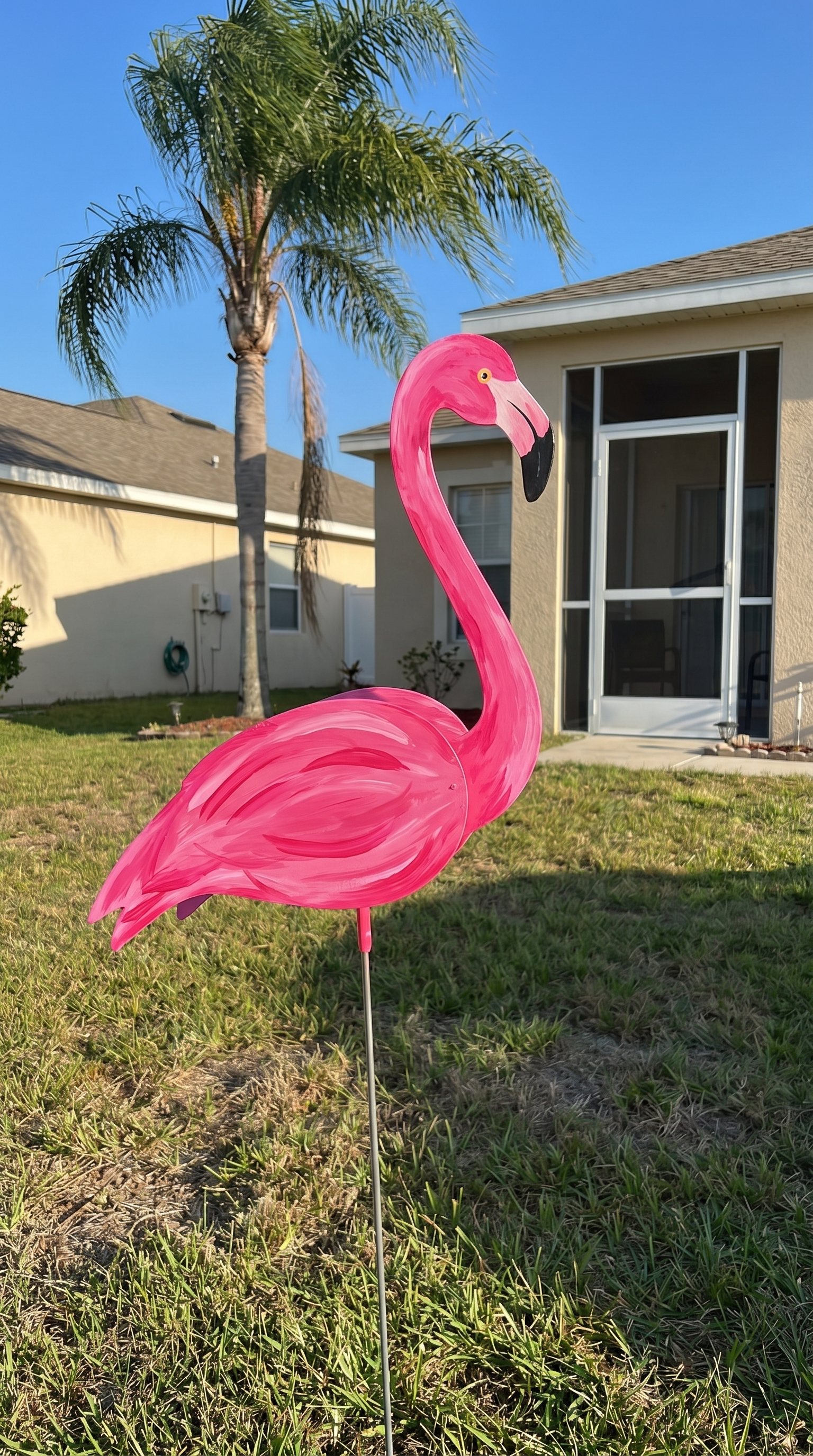 Customer photo: Hot pink flamingo wind-spinner in a Florida palm tree yard