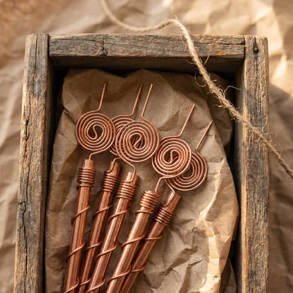 Top-down view of five Henri's Plant-Boosting copper garden stakes packed neatly in an aged wooden crate with brown craft paper and natural twine, ready to ship.