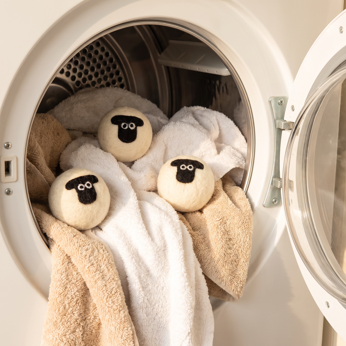 Three sheep wool dryer balls in a dryer drum with towels
