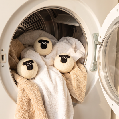 Three sheep wool dryer balls in a dryer drum with towels