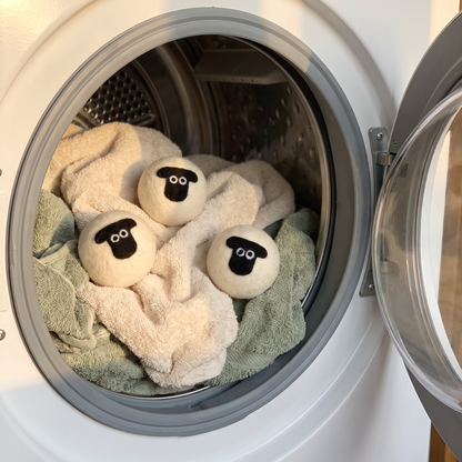 Three sheep wool dryer balls in a dryer drum with towels